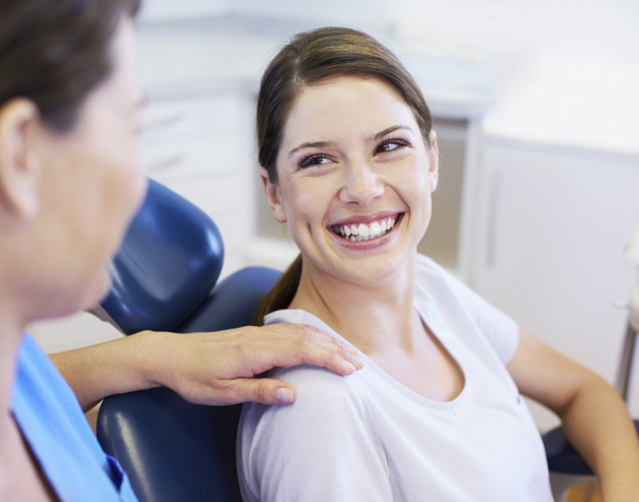 a smiling patient with a doctor's hand on her shoulder